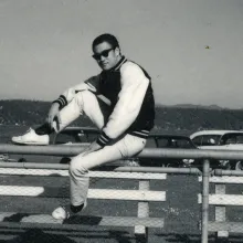 A man is sitting on a ledge in parking lot