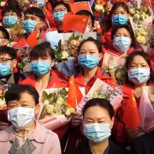 A group of people all wearing face masks waving the Chinese flag.
