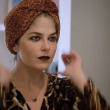 A woman with white skin wearing a head scarf and cheetah print top.