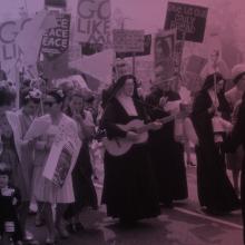 A group of people protesting, including several nuns in black robes.