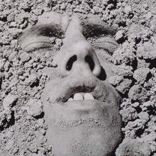 A black and white portrait of a white man submerged in dirt. David Wojnarowicz, Untitled (Face in Dirt), 1991. © Estate of David Wojnarowicz. Courtesy of the Estate and P·P·O·W.