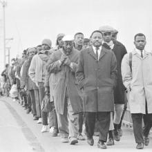 A group of Black man marching over a bridge