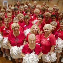An elderly cheerleading team, all wearing red tshirts and white skirts
