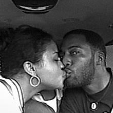 Old picture of a Black couple in the car, giving each other a kiss