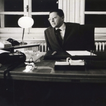 Kikhia leans over his mid-20th century style desk