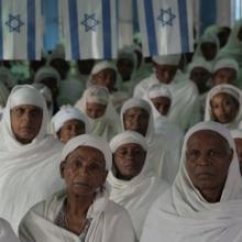 Ethiopian Jewish Women dressed in white sit during a Sunday service in a synagogue