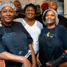 Group of African-American is smiling at the camera in a kitchen.