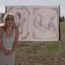 Three people standing in front of a drawing of human genetalia.