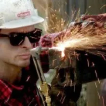 man in white hard hat soldering. 