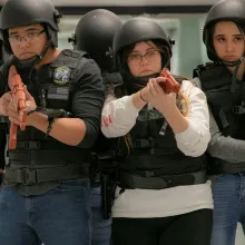 A group of high school students are in training, wearing tactical vest, helmets and fake guns