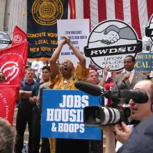 an ACORN political activist speaks in front of crowd and fellow supporters waiving signs