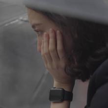 Film still of a pensive Shiori under an umbrella, face in hand