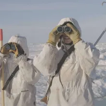 Young hunters in Alaska scan an icy horizon with binoculars. 