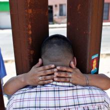 image of two people embracing eachother through the U.S/Mexico border wall