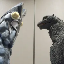 two people in Godzilla costumes stare at each other