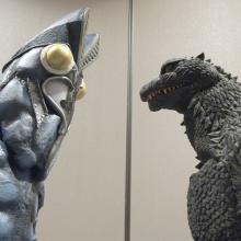 two people in Godzilla costumes stare at each other