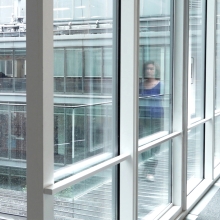 A woman is walking through a glass hallway in an art museum.