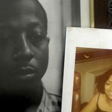A still from "For Venida, For Kalief": Two framed photos sit on a bedside cabinet, one of Kalief Browder, a young Black man wearing a checked shirt, and the other of a young Black woman wearing a sleeveless black top. 