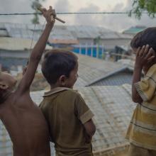 Three young boys living in a refugee camp on a rooftop playing