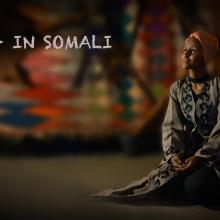 A female Somalian is sitting on the ground.