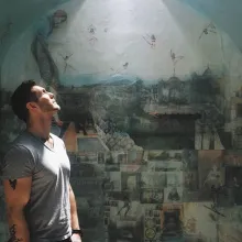 A man is looking up in front of a wall painting.