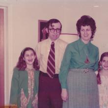 A late-20th century family photo with Mom and Dad in the middle and two daughters on either side. 