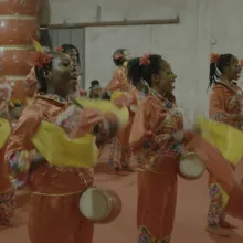 A group of Nigerian women perform a Chinese dance in traditional orange-colored Chinese dress.