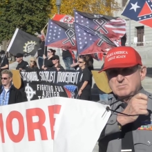 A man is holding a sign at an alt-right rally.