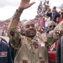 An Zimbabwe man raising his hands at crowds cheering him