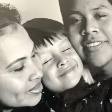 A Guatemalan mother and father smile for a photo with their adolescent son between them.