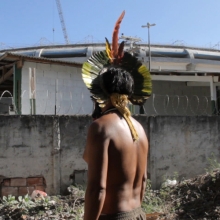 A Brazilian in traditional clothing looks at the soccer stadium outside.