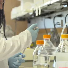 a female scientist loads a vial in a scientific lab.