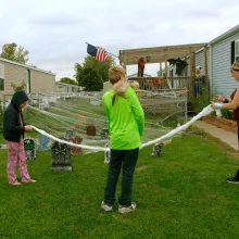 two young children hang Halloween decorations with their mother outside their mobile home