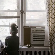 A boy and a girl is looking out at a window.