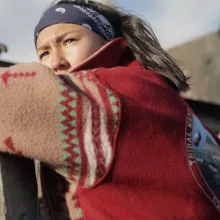 A Native American woman leaned over a fence