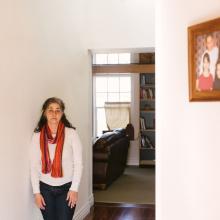 Jessica Gonzales Lenahan stands to the left of a doorway in their home with a family portrait on the right wall