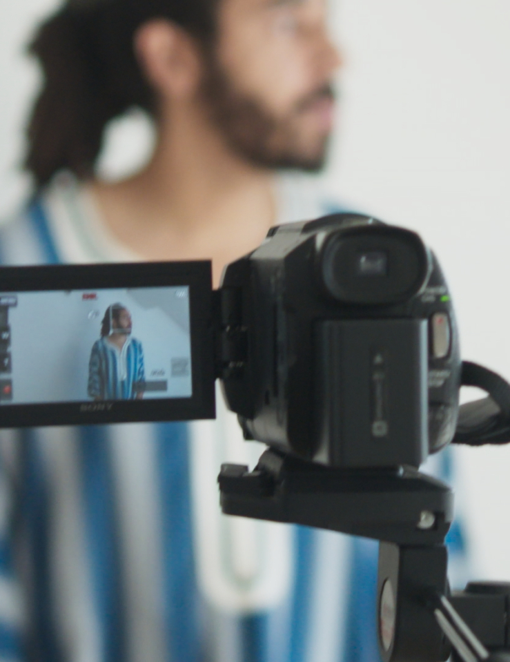 A man turns away from the camera, against a white wall.