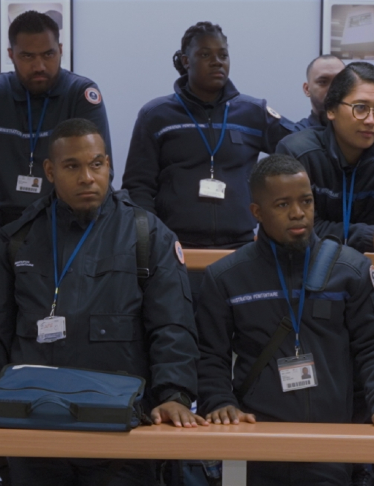 14 uniformed guards stand in two rows behind long tables